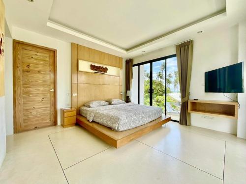a bedroom with a bed and a flat screen tv at Pina Colada in Amphoe Koh Samui