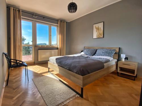 um quarto com uma cama e uma grande janela em Apartament Loft Krynica-Zdrój em Krynica-Zdrój