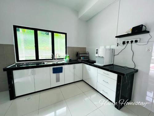 a kitchen with white cabinets and a black counter top at Haven Homestay晶晶屋 (Brand New Homestay!) in Kampong Sungai Udang