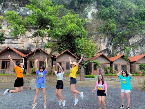 a group of people jumping in the air in front of a house at Trang An Memory Homestay in Ninh Binh