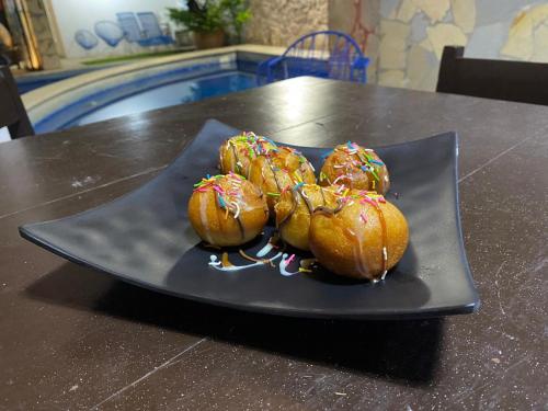 vier donuts met hagelslag op een zwarte plaat op een tafel bij Hotel Garden Suites Tonalá in Tonalá