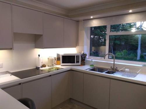 a kitchen with white cabinets and a sink and a microwave at Number Fifty-Six Ramsey Villa in Ramsey