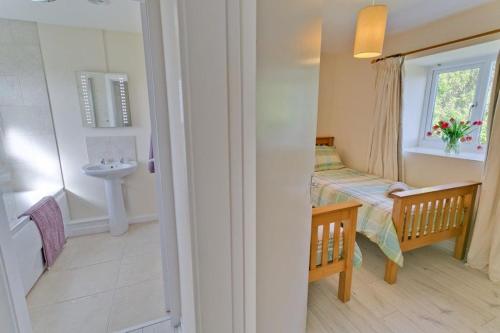 a bathroom with a bed and a sink in a room at Hideaway in Rhosneigr