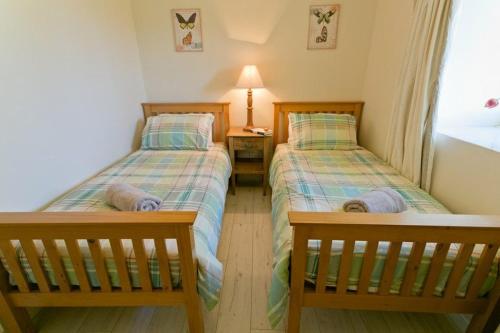 2 camas individuales en una habitación con ventana en Hideaway, en Rhosneigr