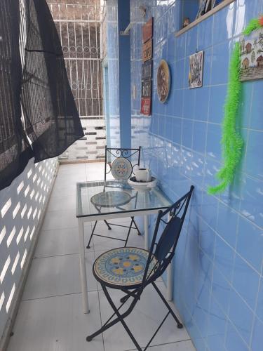 a glass table and a chair in a room at Quartos Aconchegantes prox Pelourinho, Metrô e Arena F Nova in Salvador
