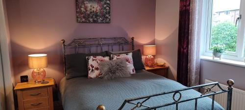 um quarto com uma cama com duas mesas de cabeceira e dois candeeiros em Cosy Retreat - house with double bedroom em Ripon