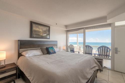 a bedroom with a bed and a view of the ocean at DBR Direct Oceanfront Condo, Daytona Beach, sleeps 6 in Daytona Beach