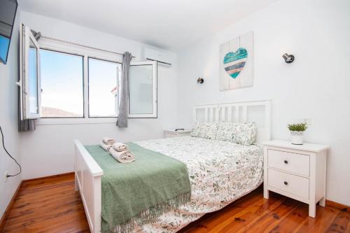 a white bedroom with a bed and a window at Hilltop Vista Apartment in Puerto Rico de Gran Canaria