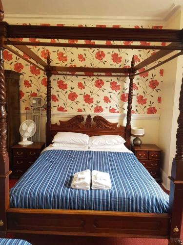 a bedroom with a canopy bed with blue and red flowers at The Lismore Hotel in Banbury