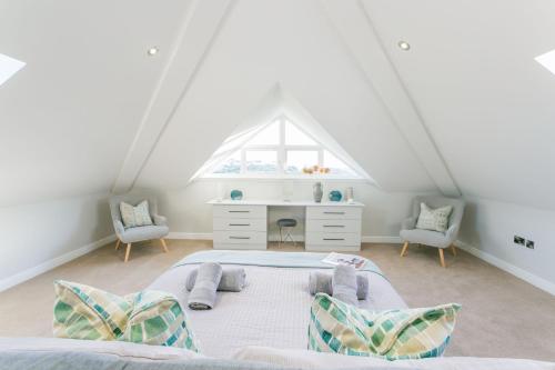 a attic bedroom with a bed and two chairs at Garreg Hen in Trearddur