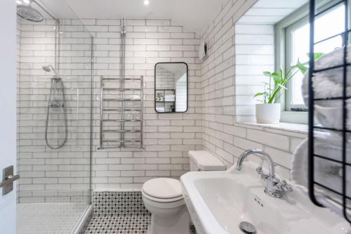 a white bathroom with a toilet and a sink at Victoria Cottage in Northrepps