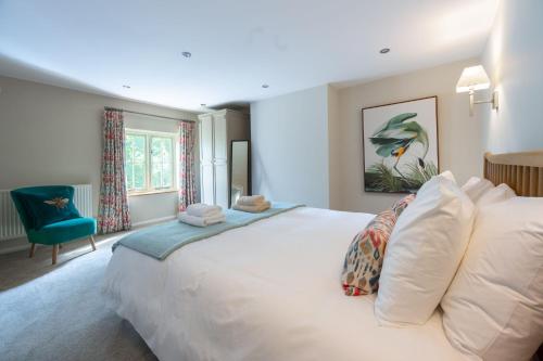 a bedroom with a large white bed and a blue chair at Victoria Cottage in Northrepps