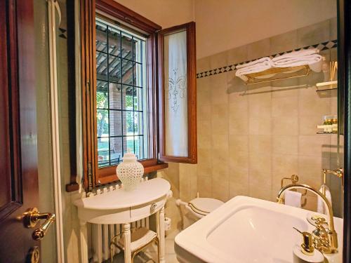 a bathroom with a sink and a toilet and a window at La casetta nel bosco in Mantova