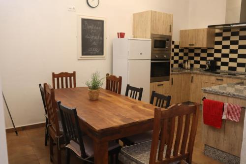 eine Küche mit einem Holztisch mit Stühlen und einem weißen Kühlschrank in der Unterkunft CASA ALEGRIA in Algodonales
