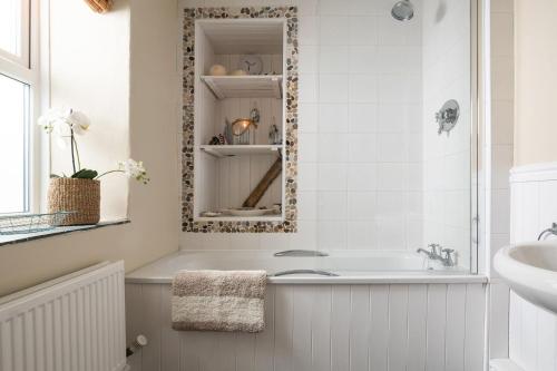 La salle de bains blanche est pourvue d'une baignoire et d'un lavabo. dans l'établissement Glandwr, à Rhosneigr