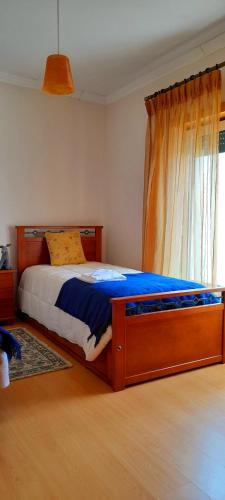 a bedroom with a bed with a wooden frame and a window at Casa dos Limões in Caldas da Rainha