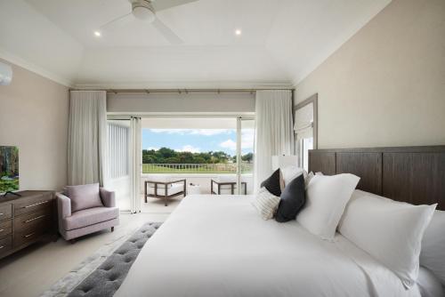 Un dormitorio con una gran cama blanca y una ventana en Apes Hill Barbados Golf and Resort Community, en Saint James
