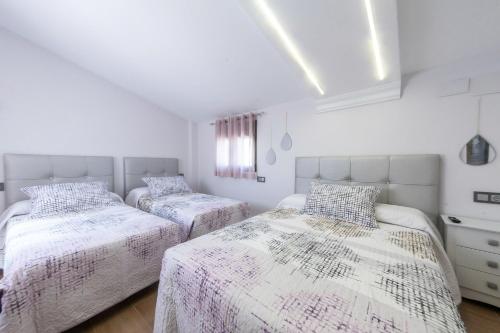VTAR Puerta Del Sol في فياكاريو: سريرين في غرفة نوم بجدران بيضاء