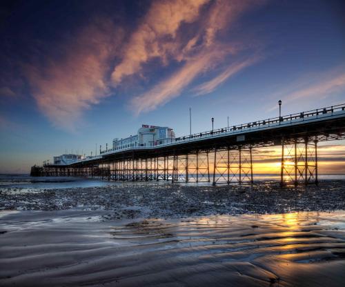 a pier on the beach at sunset with the water at Sleep Hotel in Worthing