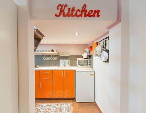 - une cuisine avec des armoires orange et un réfrigérateur blanc dans l'établissement Gallery studio apartment, à Tel Aviv