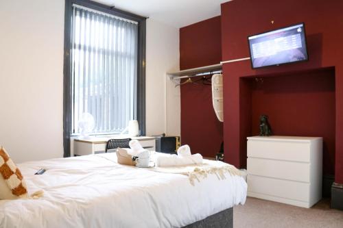 a bedroom with a white bed with a tv on the wall at Roker all ensuite Guest House in Sunderland