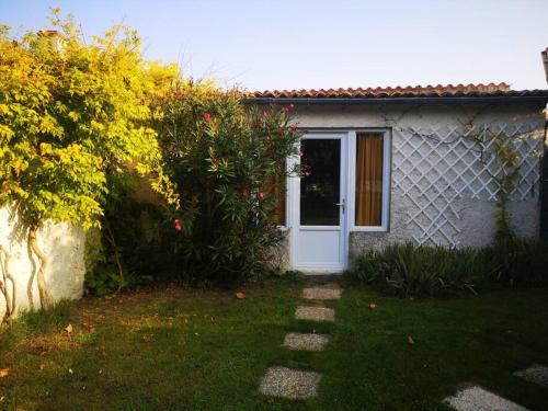 una pequeña casa con una puerta blanca en un patio en Studio neuf - accès SPA, SAUNA et Piscine Chauffée, en Saint-Vivien