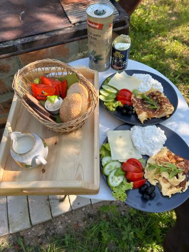 einem Picknicktisch mit zwei Teller Essen und einem Korb in der Unterkunft Lauku māja Sprīdīši 