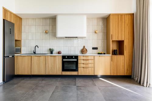 a kitchen with wooden cabinets and a white appliance at Beach Villas in Crete - Alope & Ava member of Pelagaios Villas in Ierápetra