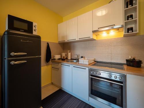 a kitchen with a black refrigerator and white cabinets at Green Apple Apartment in Subotica