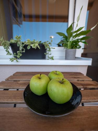 four green apples on a plate on a table at Green Apple Apartment in Subotica