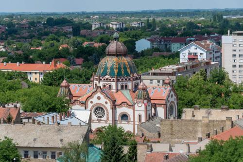 an old church with a colorful roof in a city at Green Apple Apartment in Subotica