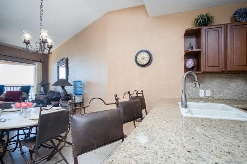 een keuken en eetkamer met een tafel en een klok aan de muur bij Sonoran Sun 2BR SE 703 by Casago in Puerto Peñasco