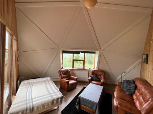 Cette chambre dispose d'un plafond avec un lit et des chaises. dans l'établissement Apartment dome Hof í Vatnsdal, à Blönduós