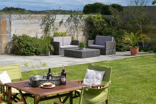 a patio with a table and chairs in a yard at Mornant in Trearddur