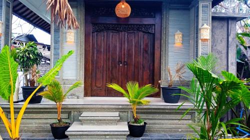 een huis met een houten deur met planten op de trap bij Regina Guest House in Ubud