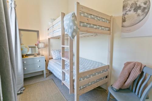 a bedroom with two bunk beds and a mirror at Penlon in Rhosneigr