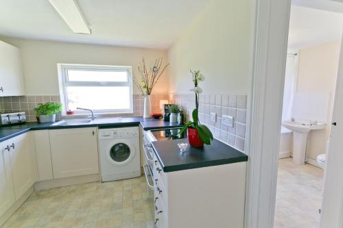 a kitchen with a washing machine and a sink at Penlon in Rhosneigr