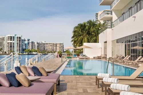ハリウッドにある2BR & 2BA Corner Suite Ocean Views at Hyde Beach House - NO FEES till Dec 31, 2025の建物の隣にスイミングプール(長椅子付)があります。
