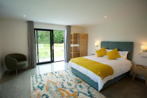 um quarto com uma cama, uma cadeira e uma janela em Dillon School House - Luxury in the countryside em Roscommon
