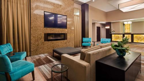 uma sala de estar com um sofá e uma televisão na parede em Best Western Plus Lamplighter Inn & Conference Centre em London