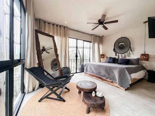 een slaapkamer met een bed, een stoel en een spiegel bij Vida Jungle Boho Apart 14 with special fee to access Hotel Bardo in Tulum