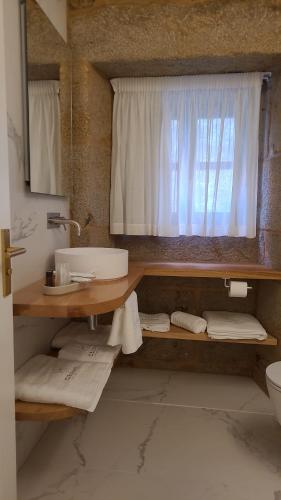 baño con lavabo, espejo y ventana en hostal Hcelenis, en Caldas de Reis