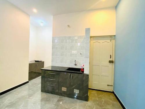 a kitchen with a black counter and a door at Pal's Cottage in Mysore