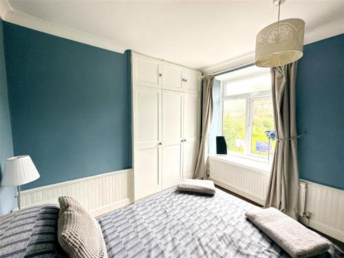 1 dormitorio con paredes azules, 1 cama y ventana en Cute Country Cottage near Leeds & York, en Leeds