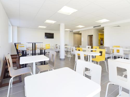 a room with white tables and yellow chairs at Premiere Classe Valence Nord - Saint Marcel Les Valence in Saint-Marcel-lès-Valence