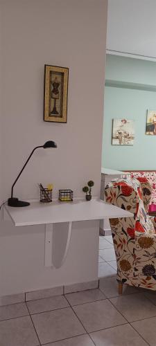 a white desk with a lamp next to a chair at Daphne's apartment in Kavala