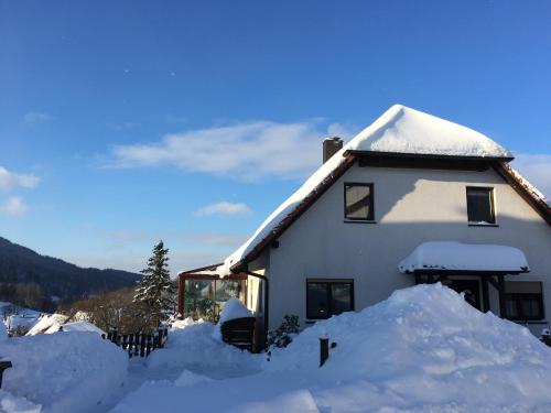 ein schneebedecktes Haus mit einem Schneehaufen in der Unterkunft Ferienwohnung Rennsteigblick in Suhl