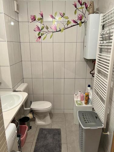 ein Badezimmer mit einem WC und einem Waschbecken mit Blumen an der Wand in der Unterkunft Apartment Sunny day in Livno