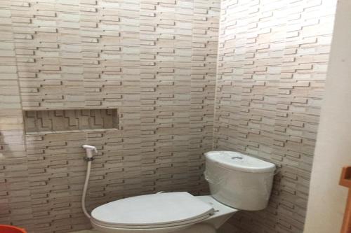 ein Badezimmer mit einem weißen WC und einer Ziegelwand in der Unterkunft OYO 93088 Celine Home Syariah in Parit