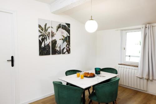une salle à manger avec une table blanche et des chaises vertes dans l'établissement Le T2 Chic !, à Carcassonne